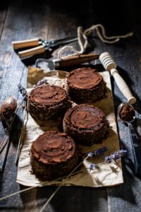 Mini chocolate cakes on a paper with a spoon and tools